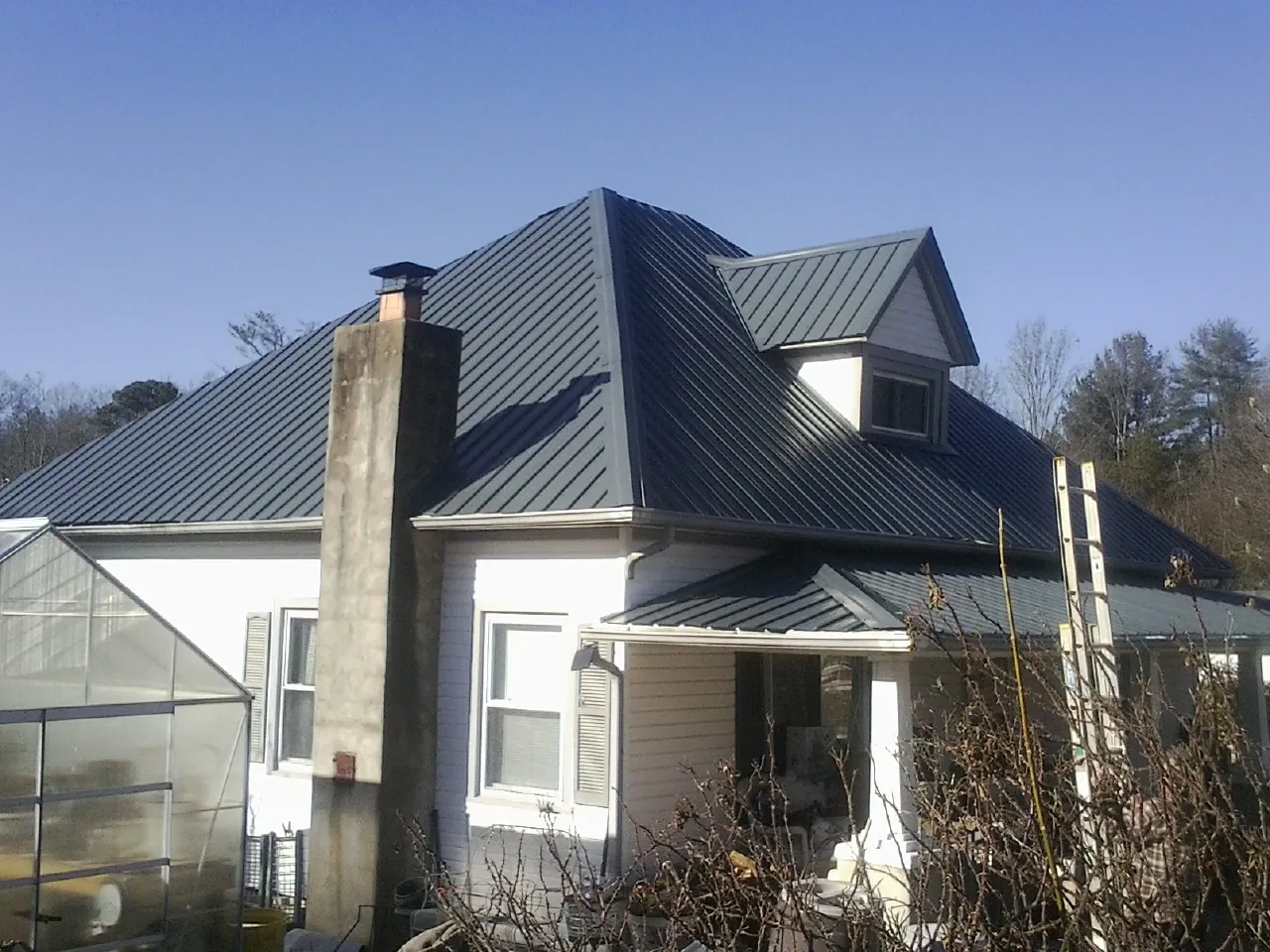 Dark blue standing seam metal roof on a white farmhouse with dormer — Slate & Tile Roof Repair by Roofing Brothers in Marcola