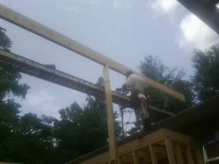 Carpenter setting a ridge beam over a new addition frame — Ice Dam Removal by Roofing Brothers in Marcola