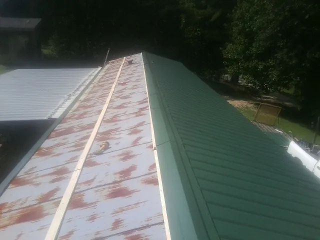 Old rusted panels beside newly installed green metal roofing — Wind Damage Roof Repair by Roofing Brothers in Marcola