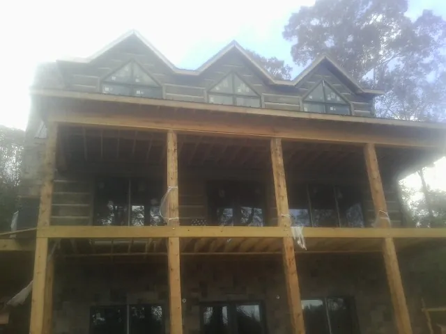Dormers and porch framing on a large log home under construction — Roof Coating work by our crew in Marcola