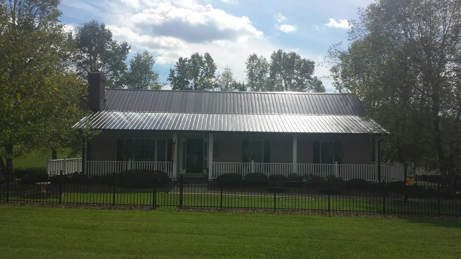 Gray metal roof on a brick ranch with a full width front porch — Gutter Guard Installation work by our crew in Marcola