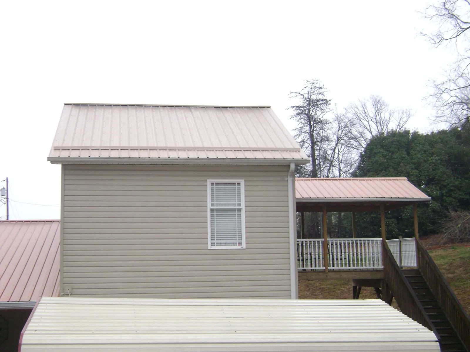 Tan metal roofs on a two story addition and attached porch, from a Roof Replacement job in Marcola