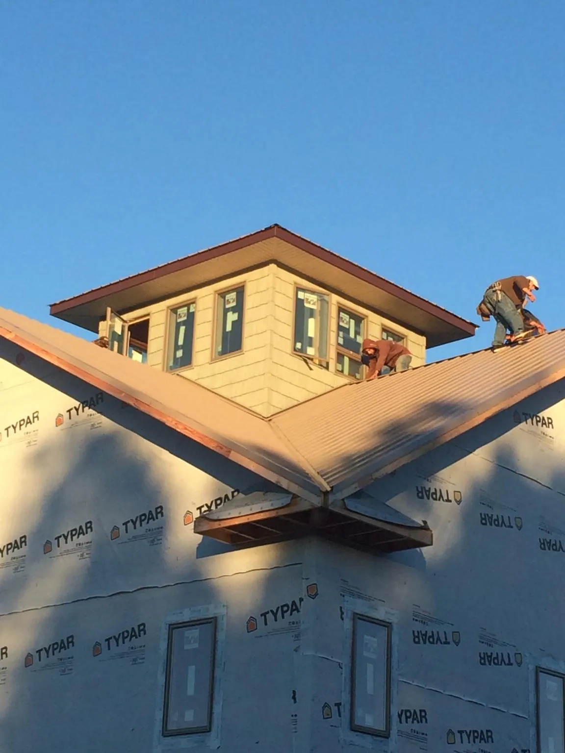 Roofers working around a rooftop cupola on a new metal roof at sunset — Roof Waterproofing in Marcola by Roofing Brothers